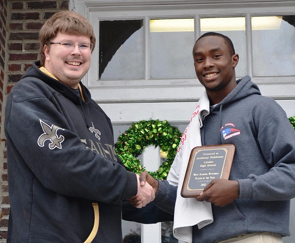 Anthony Robinson of Linden High School receives a commemorative plaque and T-shirt from Jeremy D. Smith.  Robinson was selected as the first recipient of the West Alabama Watchman All-County Team's Player of the Year award.