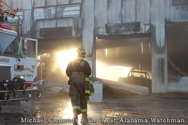 12-18-2012 -- Demopolis, Ala. -- Early morning sun reveals the damage caused by a fire at Newton Tire, as Demopolis fireman Justin King walks by.