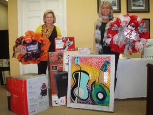 Laurie Willingham and Jenn Tate show off some of the items donated to be auctioned off in a benefit the Demopolis Chamber of Commerce during Monday's Chamber celebration. 