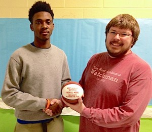 Michael Moore receives a commemorative basketball from West Alabama Watchman Managing Partner Jeremy D. Smith for earning the WAW Player of the Year Award.