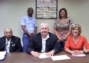Marengo County Schools Superintendent Luke Hallmark (center) and MCS Board Member Arthur Hopson (left) sign the system's UWA Teacher Connect agreement to provide lowered tuition rates for teachers within the system who wish to pursue advanced degrees at the University of West Alabama. Pictured at right is Lisa Compton, UWA Online Recruiting Director. Standing, left to right, are MCS Technology Coordinator William Martin and Marengo County Federal Programs Coordinator Stephanie Pope.