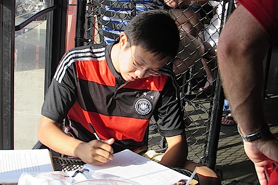 Jeremy Chu registers for the Demopolis Elite program during Monday's World Cup kickoff party.