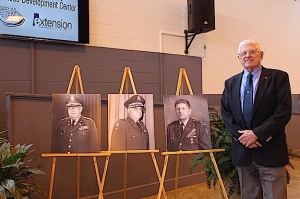 Col. Thomas Boggs Jr. stands next to photos of the three men for whom the center is named.