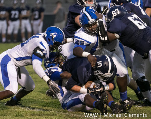 Rahmeel Cook (44), Marcus Wright (bottom) and Erin White (45) stop Jemison's quarterback behind the line of scrimmage.